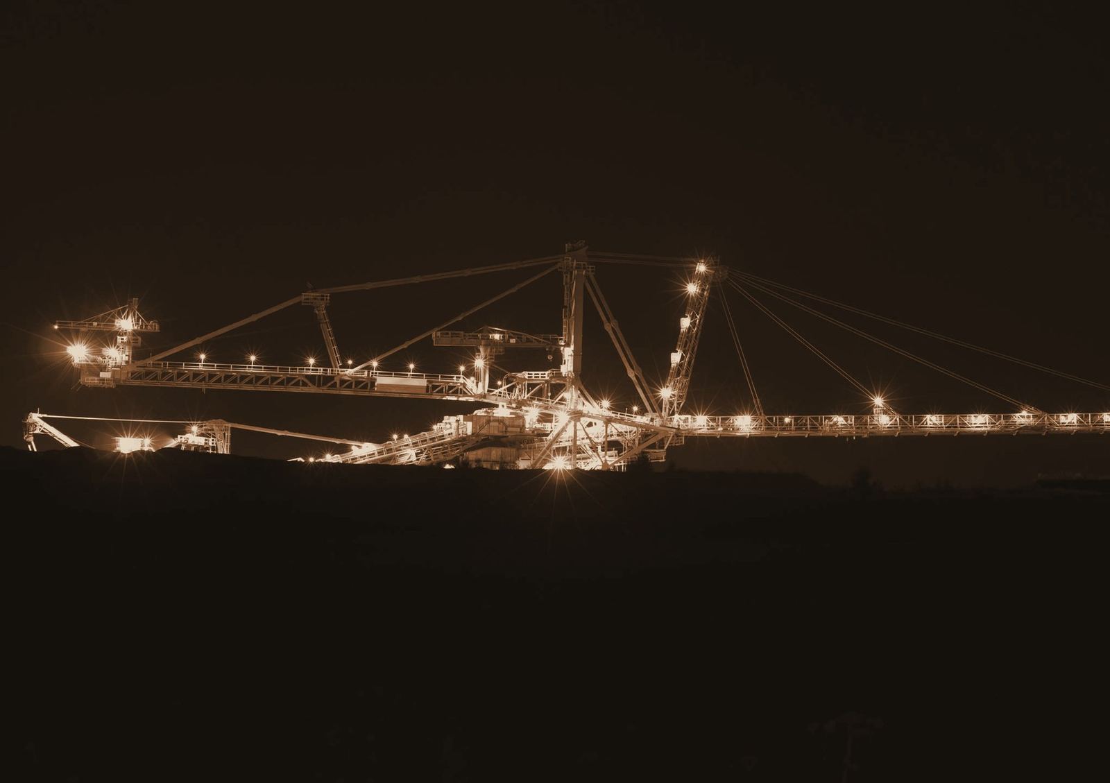 Mining stacker-reclaimer and conveyor structure lit up during night operations